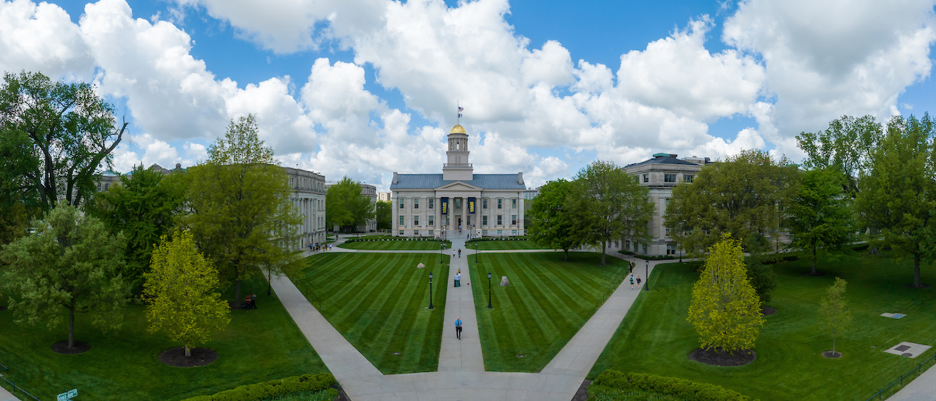 Drone image of Pentacrest with Old Capital centered with blue sky and green lawn